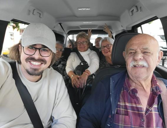 Grupo de personas mayores y joven sonrientes dentro de un coche durante desplazamiento conjunto
