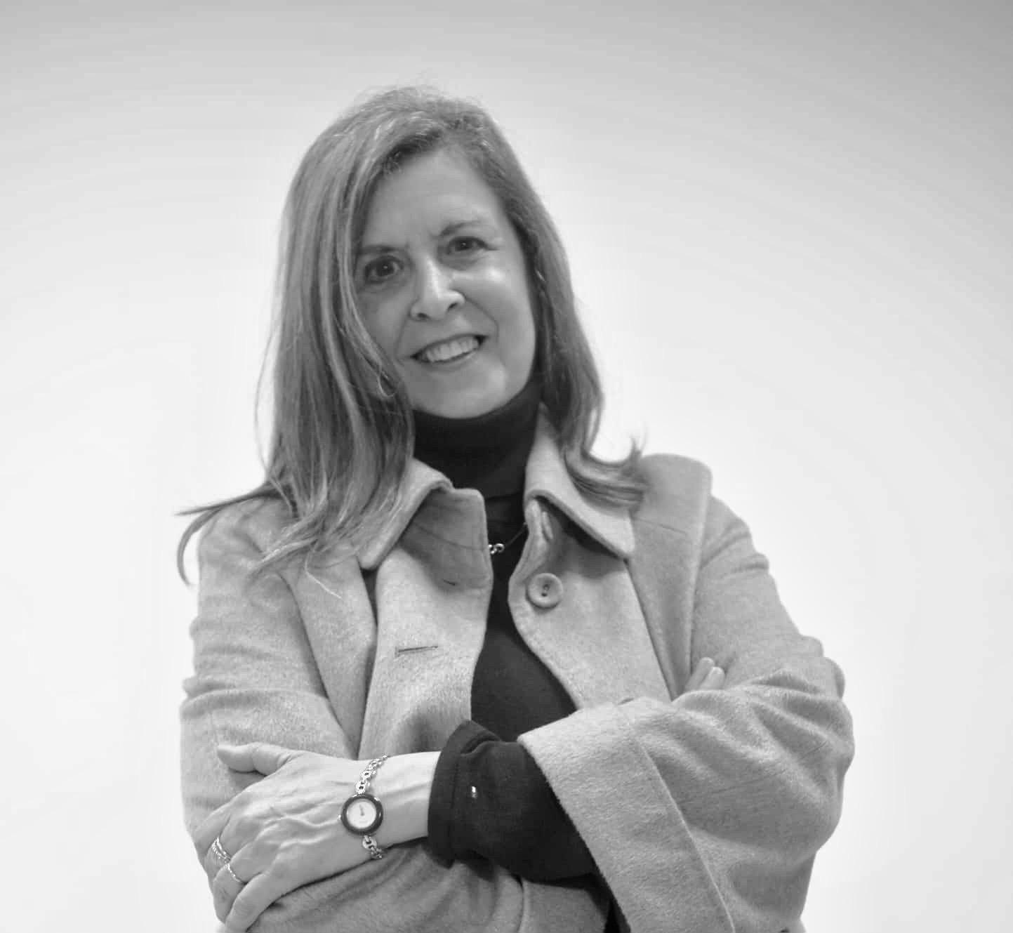 Retrato en blanco y negro de María de las Mercedes Domínguez Hernández sonriendo con brazos cruzados sobre fondo neutro