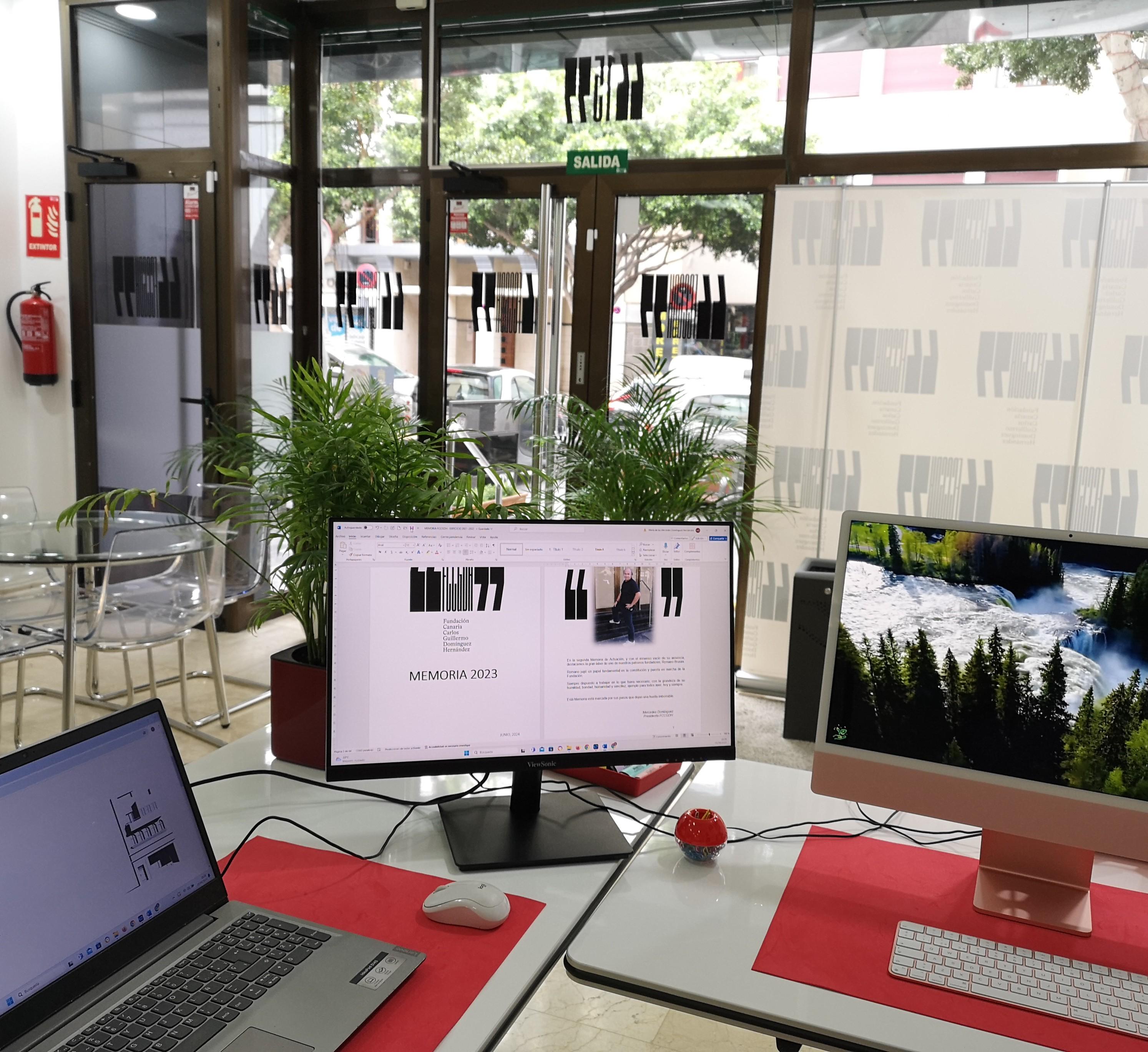 Espacio de trabajo con ordenadores mostrando documentos de la fundación en una oficina luminosa