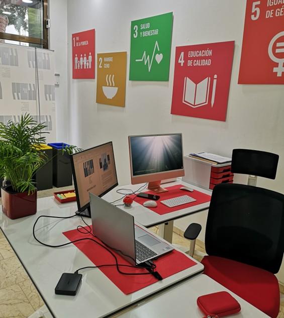 Espacio de trabajo moderno con ordenadores y carteles de objetivos de desarrollo sostenible en la pared
