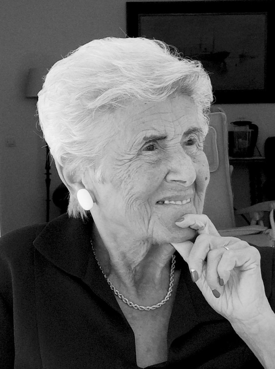 Retrato en blanco y negro de María Mercedes Hernández Martín sonriente, presidenta Honorífica, con mano en el mentón, expresión serena en interior doméstico